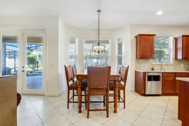 dining space featuring light tile patterned floors, french doors, a notable chandelier, and sink