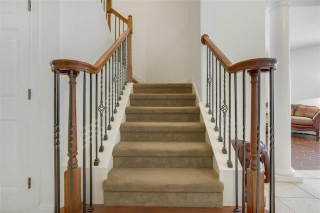 stairway with tile patterned floors and decorative columns