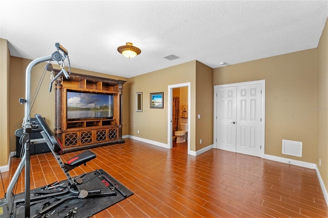 exercise area with wood-type flooring and a textured ceiling