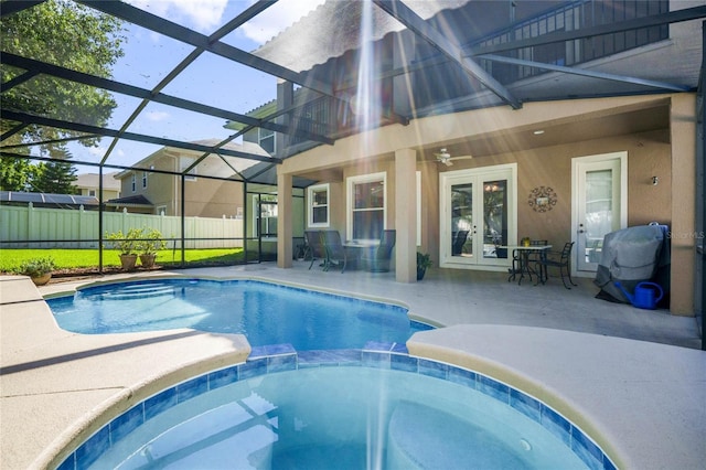 view of swimming pool with glass enclosure, ceiling fan, french doors, a patio area, and an in ground hot tub