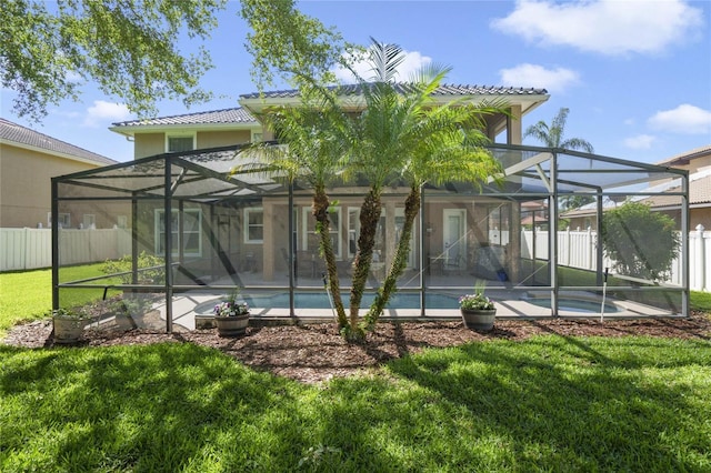 back of property with a yard, a fenced in pool, and glass enclosure