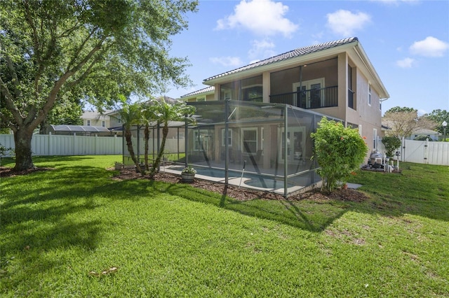 rear view of house with glass enclosure, a fenced in pool, and a yard