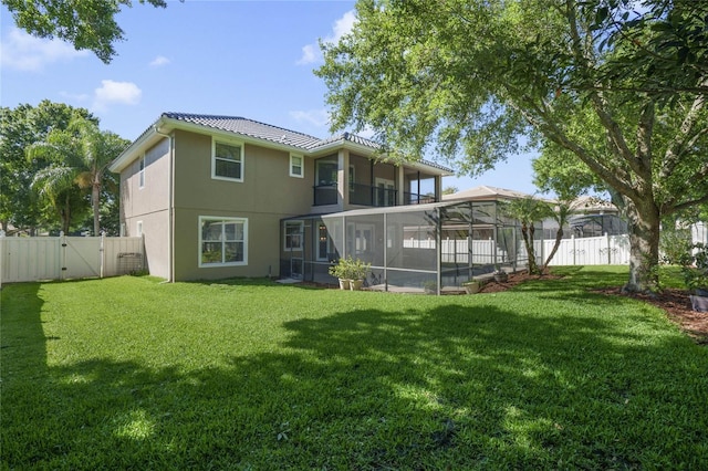 back of house featuring a yard, glass enclosure, and a sunroom