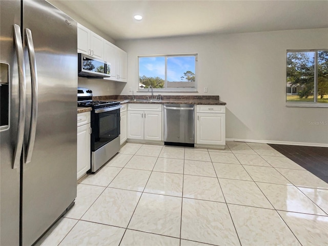 kitchen with white cabinets, stainless steel appliances, light tile patterned flooring, and sink