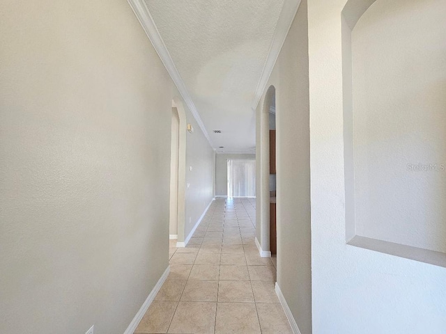 hall with a textured ceiling, light tile patterned floors, and crown molding