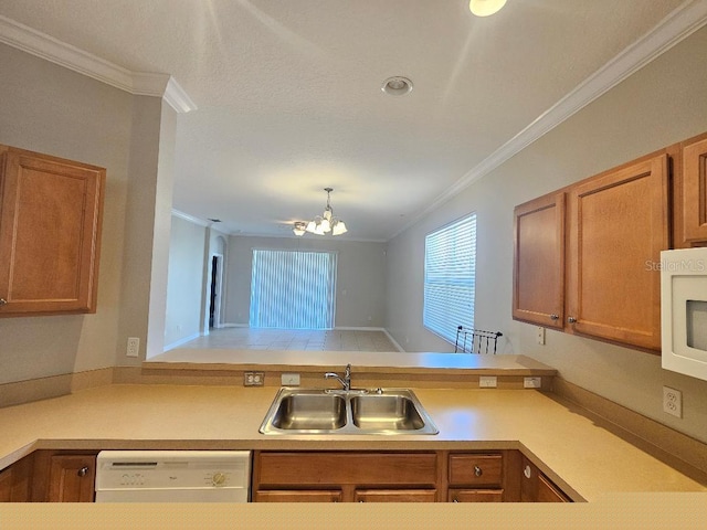 kitchen featuring kitchen peninsula, ornamental molding, white appliances, sink, and a chandelier