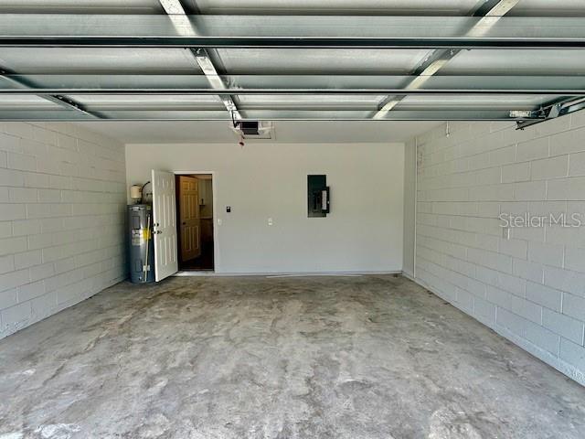 garage with a garage door opener, electric water heater, and electric panel