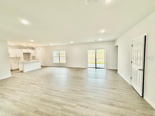 unfurnished living room featuring sink and light hardwood / wood-style floors