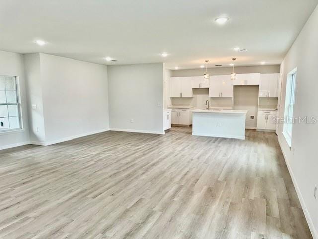 unfurnished living room featuring sink and light hardwood / wood-style floors