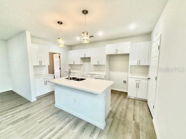 kitchen with backsplash, sink, white cabinets, and hanging light fixtures