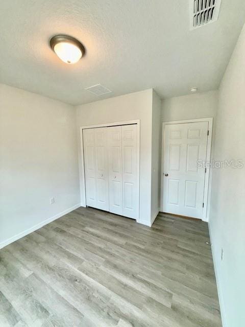 unfurnished bedroom featuring light hardwood / wood-style floors and a closet