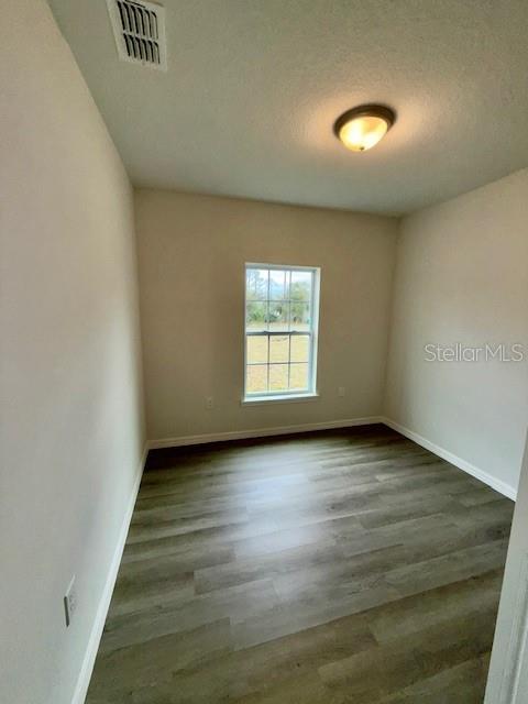 spare room featuring dark hardwood / wood-style flooring and a textured ceiling