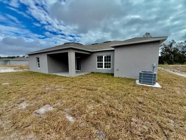 rear view of property with a lawn and central air condition unit