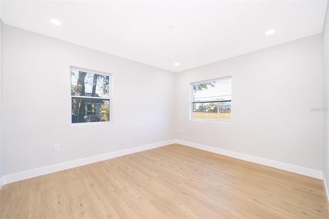 empty room with light hardwood / wood-style floors and a healthy amount of sunlight