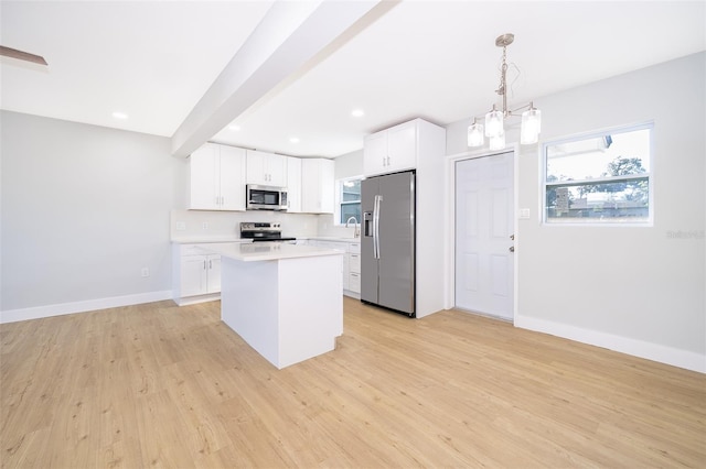 kitchen with white cabinets, decorative light fixtures, a kitchen island, and stainless steel appliances