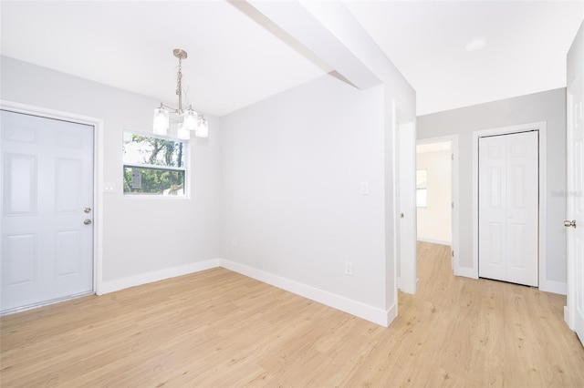 spare room with an inviting chandelier and light hardwood / wood-style flooring