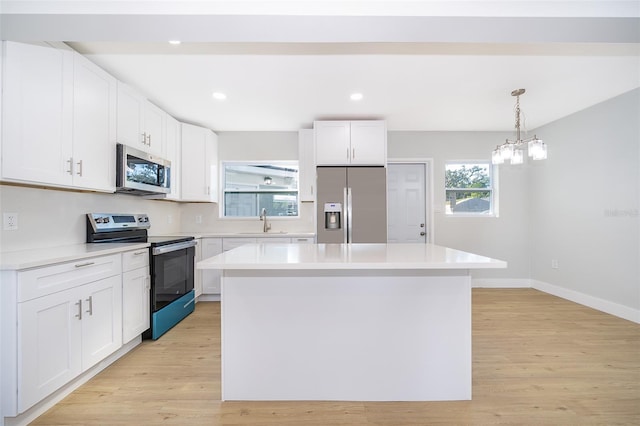 kitchen with white cabinetry, sink, appliances with stainless steel finishes, a kitchen island, and light wood-type flooring