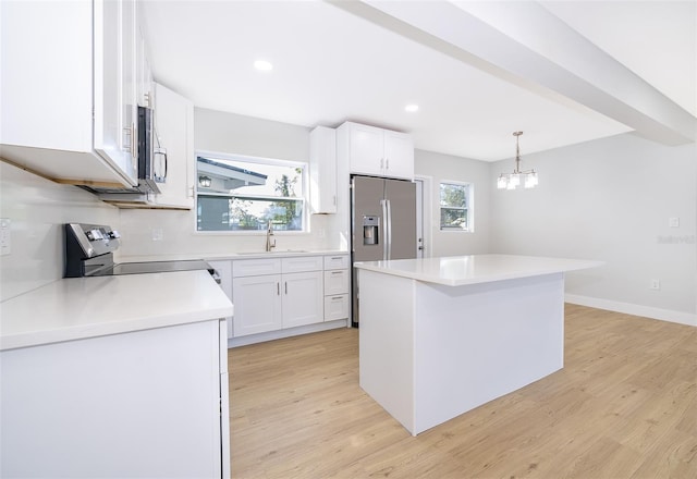 kitchen featuring hanging light fixtures, white cabinets, appliances with stainless steel finishes, a kitchen island, and light wood-type flooring