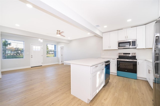 kitchen with white cabinets, appliances with stainless steel finishes, a kitchen island, and ceiling fan