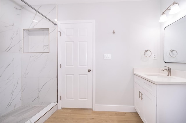 bathroom with tiled shower, wood-type flooring, and vanity