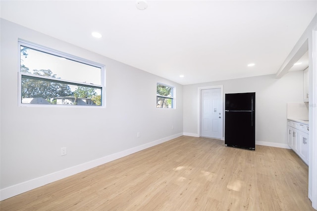 unfurnished bedroom featuring black fridge and light hardwood / wood-style flooring