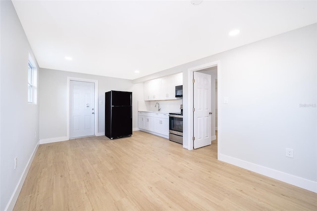 kitchen featuring sink, light hardwood / wood-style floors, white cabinetry, and black appliances