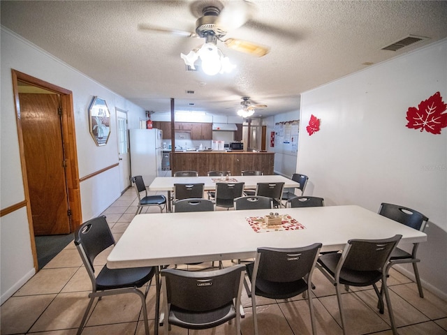 tiled dining area with ceiling fan and a textured ceiling