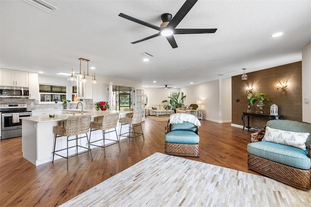 living room with light hardwood / wood-style flooring, ceiling fan, and sink