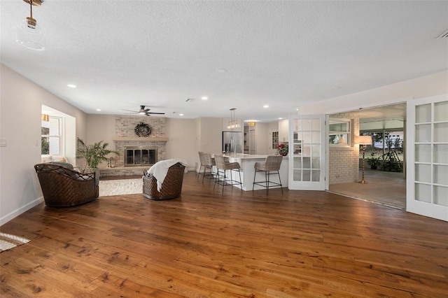 living room featuring a textured ceiling, dark hardwood / wood-style floors, ceiling fan, and a fireplace