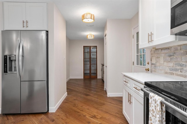 kitchen featuring backsplash, a textured ceiling, stainless steel appliances, hardwood / wood-style floors, and white cabinetry