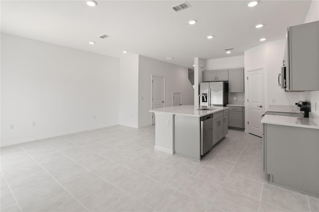 kitchen featuring appliances with stainless steel finishes, a kitchen island with sink, sink, gray cabinets, and light tile patterned flooring