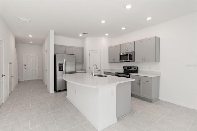 kitchen featuring light tile patterned floors, an island with sink, stainless steel appliances, and sink