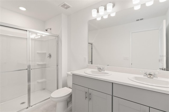 bathroom featuring tile patterned flooring, vanity, toilet, and a shower with shower door