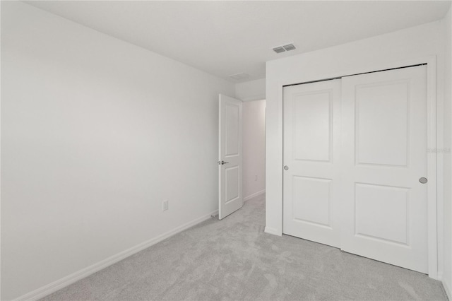 unfurnished bedroom featuring light colored carpet and a closet