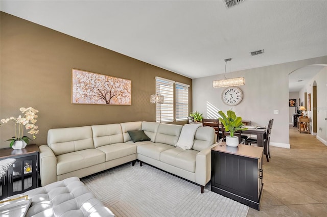 living room with light tile patterned floors and an inviting chandelier