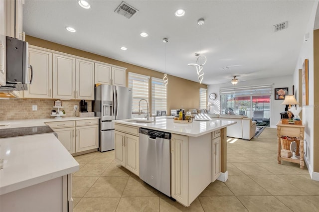 kitchen with ceiling fan, sink, hanging light fixtures, stainless steel appliances, and a kitchen island with sink