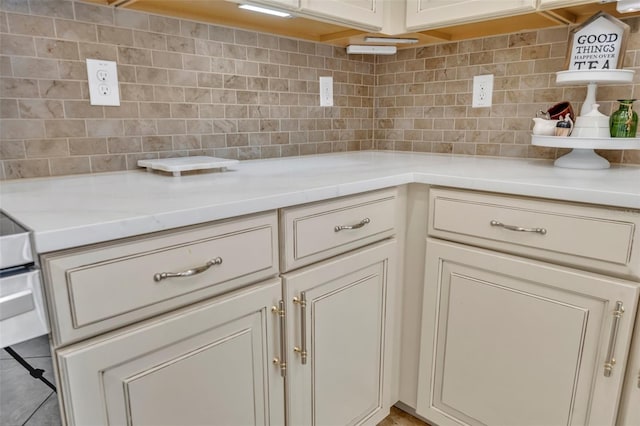 kitchen featuring tile patterned floors, decorative backsplash, cream cabinets, and light stone counters