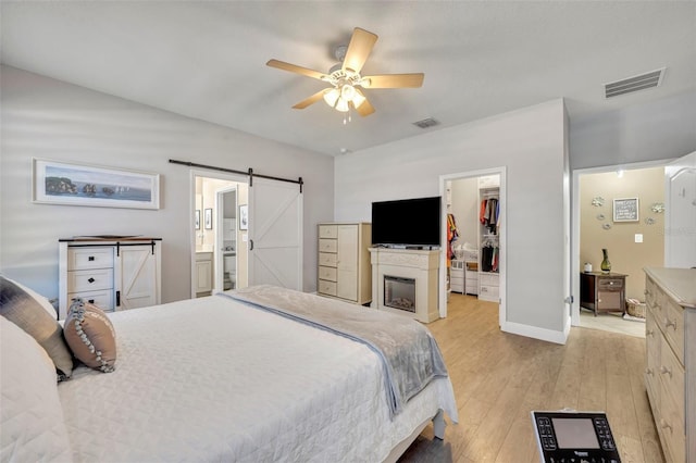 bedroom featuring ensuite bath, ceiling fan, a barn door, a spacious closet, and a closet