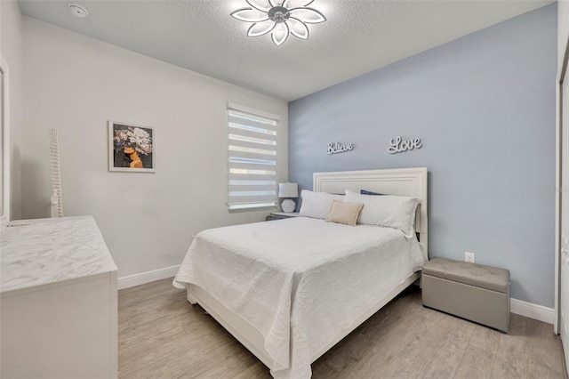 bedroom featuring a textured ceiling and light hardwood / wood-style flooring