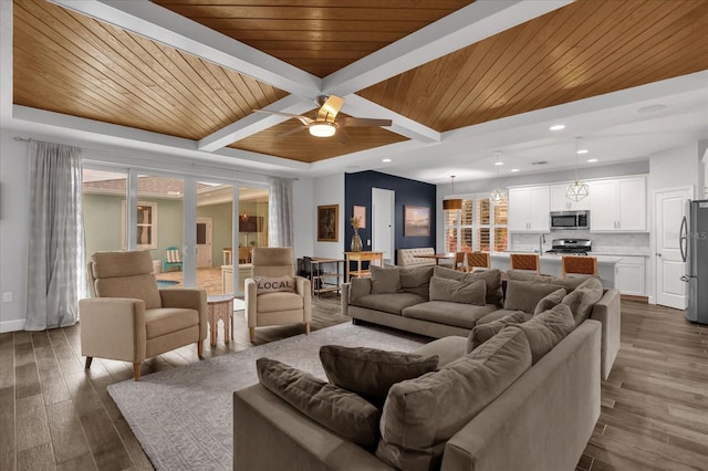 living room with beam ceiling, ceiling fan, dark wood-type flooring, and wood ceiling