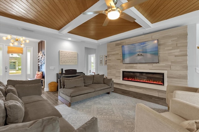 living room featuring beamed ceiling, ceiling fan with notable chandelier, wood ceiling, and a tile fireplace