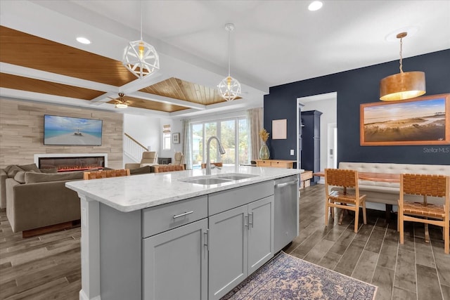 kitchen with pendant lighting, stainless steel dishwasher, a kitchen island with sink, and sink