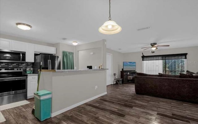 kitchen featuring decorative backsplash, appliances with stainless steel finishes, dark wood-type flooring, pendant lighting, and white cabinetry