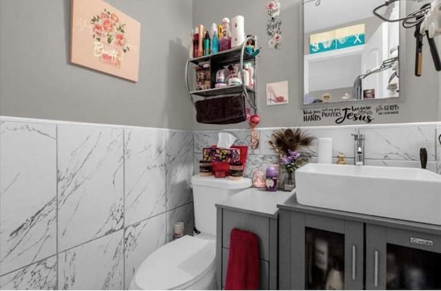 bathroom with vanity, toilet, and tile walls