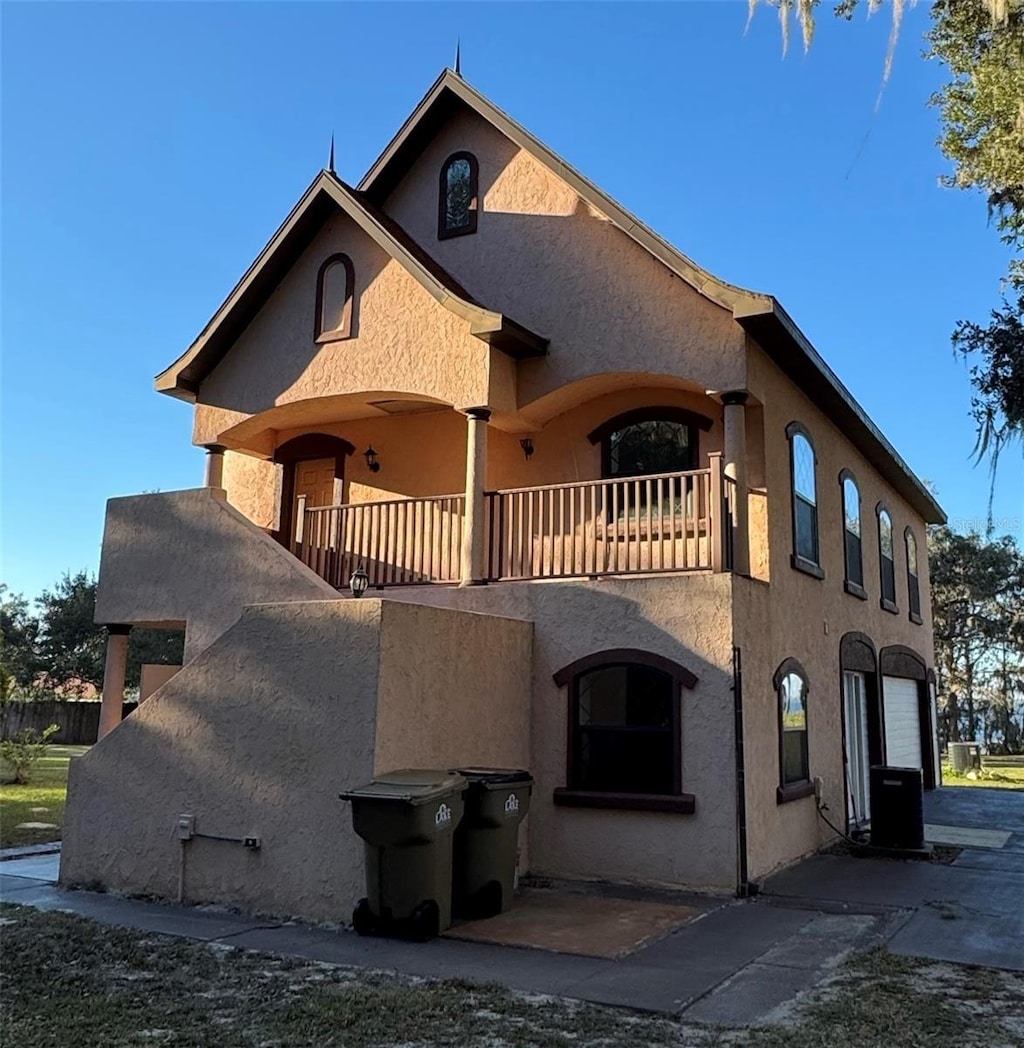 view of front facade with central air condition unit, a balcony, and a garage