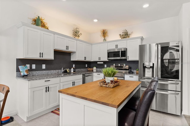 kitchen featuring white cabinets, appliances with stainless steel finishes, light tile patterned floors, and a kitchen island