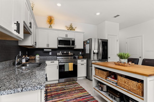 kitchen featuring decorative backsplash, white cabinetry, sink, and appliances with stainless steel finishes