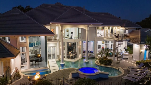 pool at twilight featuring a patio area and an in ground hot tub