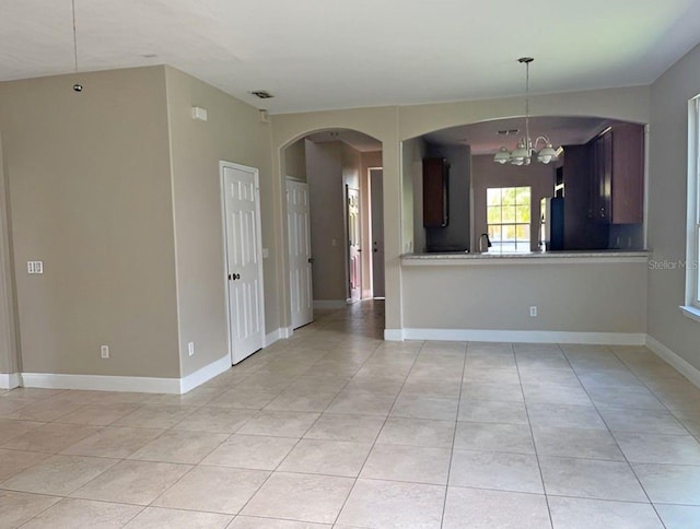 tiled empty room with an inviting chandelier