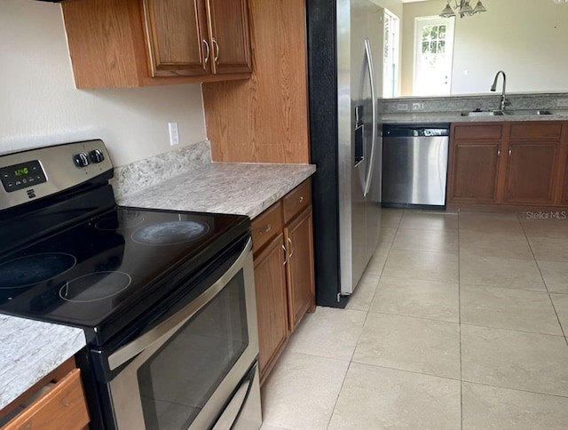 kitchen with sink, light tile patterned floors, a chandelier, and appliances with stainless steel finishes